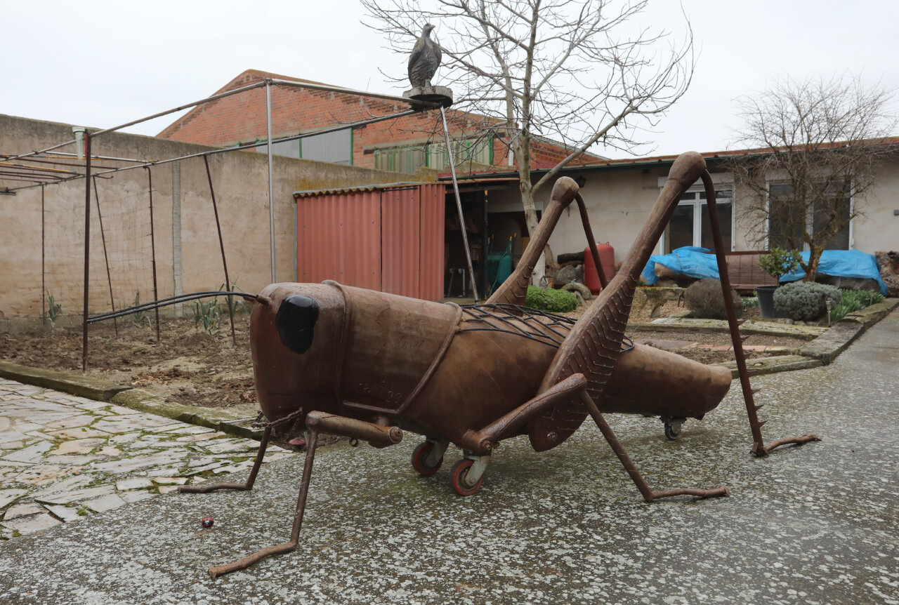 Escultura de un saltamontes de hierro en un taller al aire libre