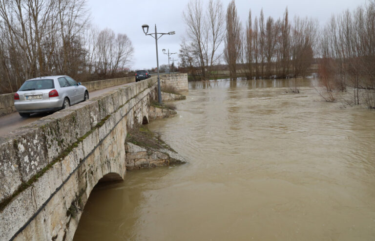 Puente sobre un río con agua alta y vehículos pasando