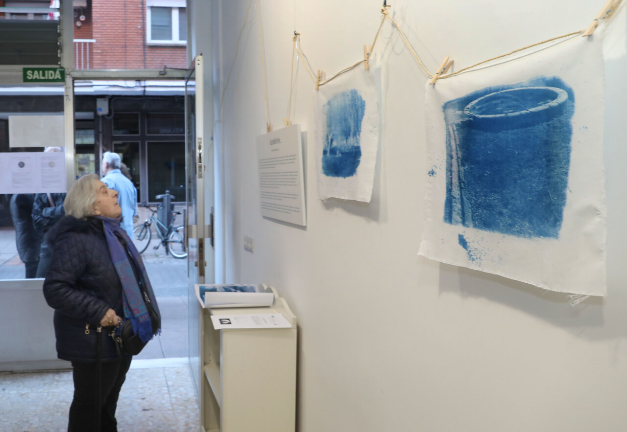 Mujer observando obras de cianotipia en exposición sobre lavaderos