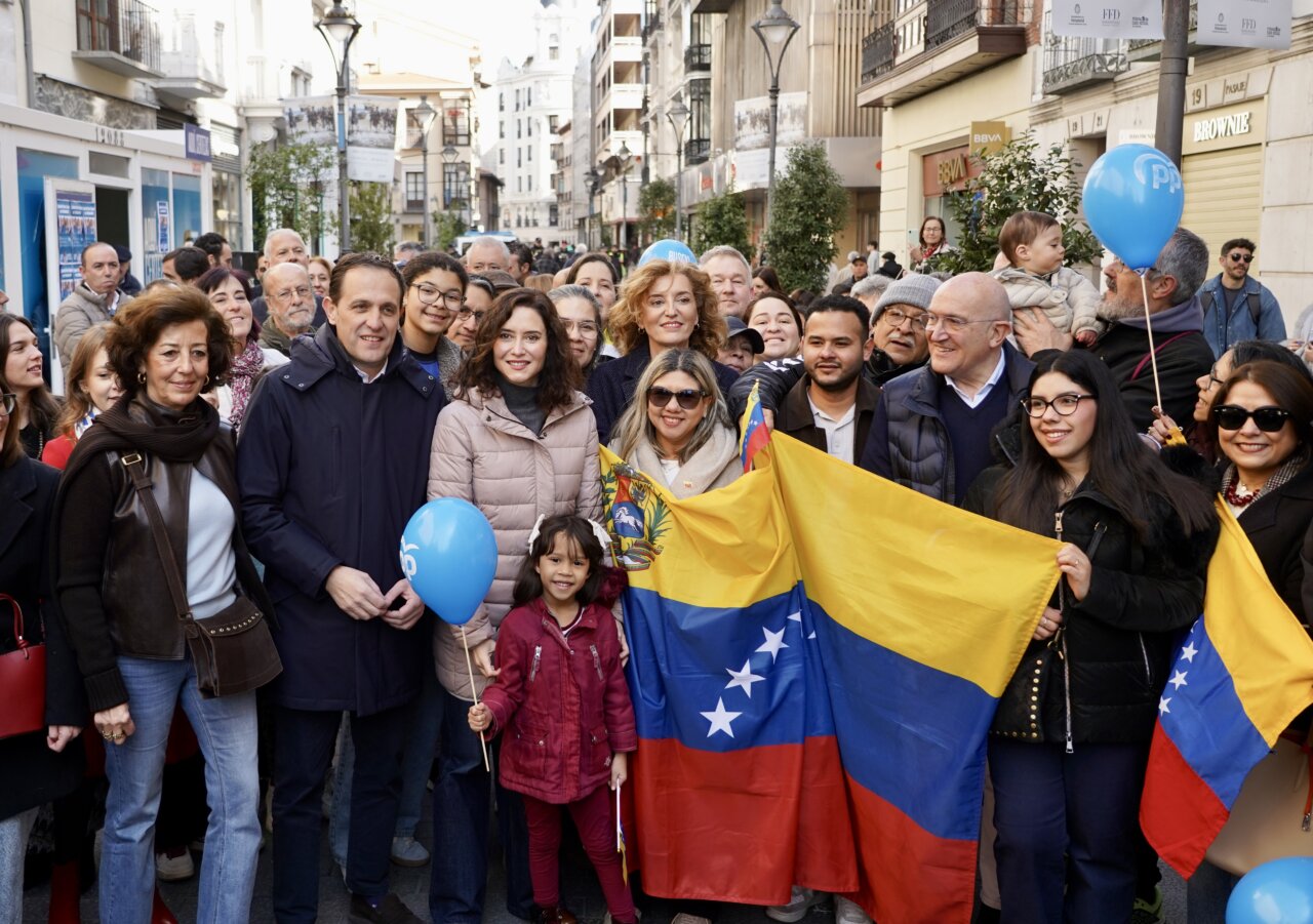 Ayuso y grupo de personas con banderas en evento político
