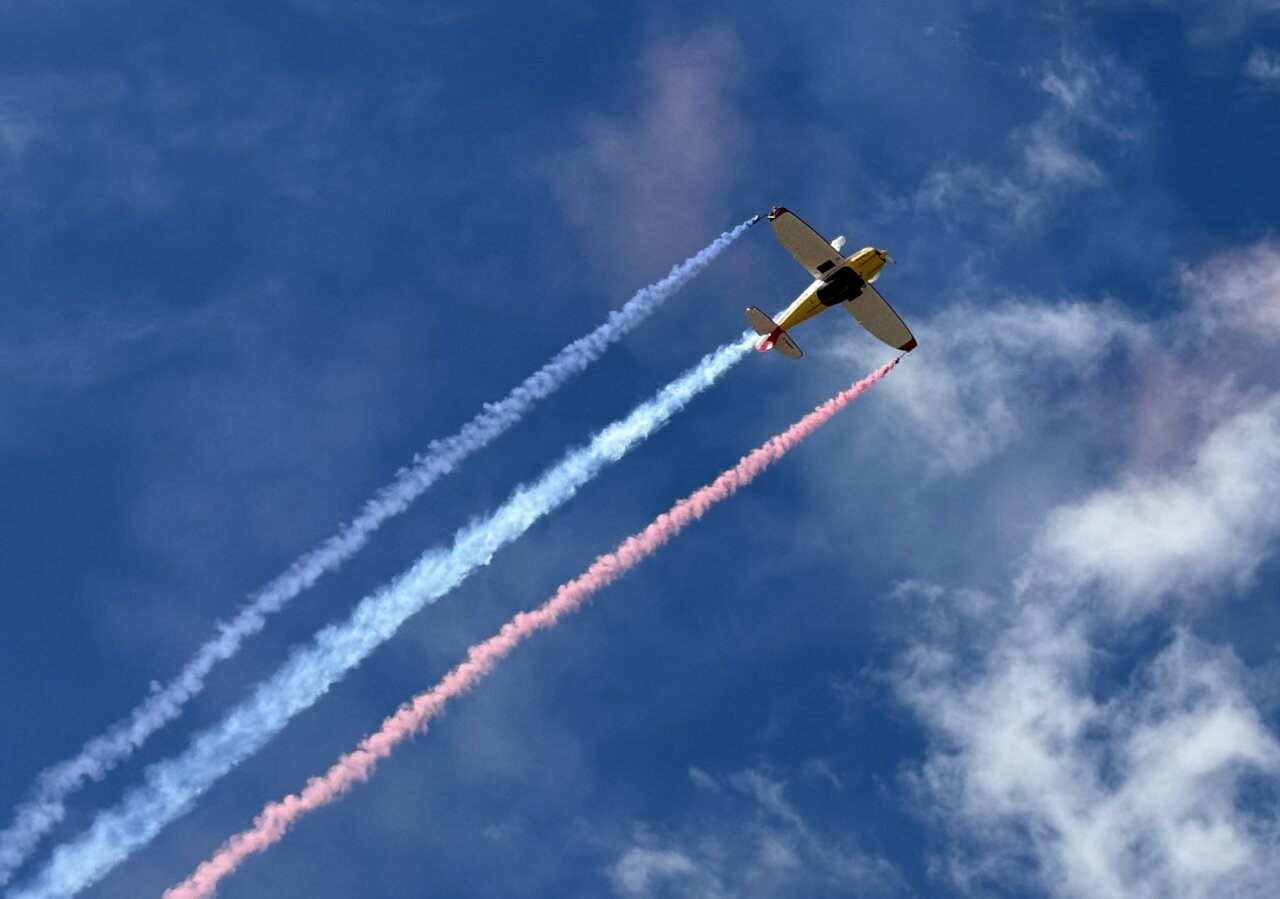 Avión realizando acrobacias aéreas con humo de colores en el cielo