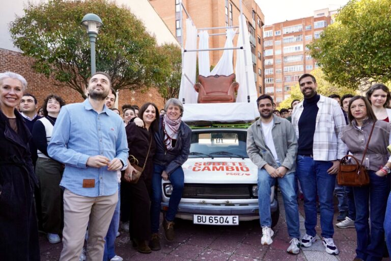 Grupo de personas en un evento político en Valladolid con un coche decorado