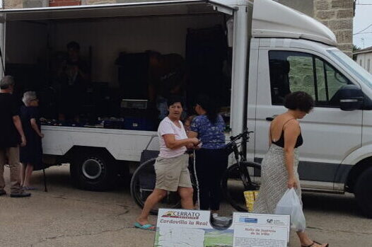 Comerciantes y vecinos en un mercado rural con un vehículo de venta ambulante