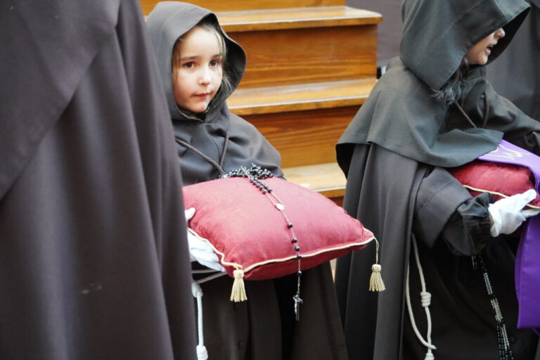 Niña con hábito sosteniendo un cojín en una procesión religiosa