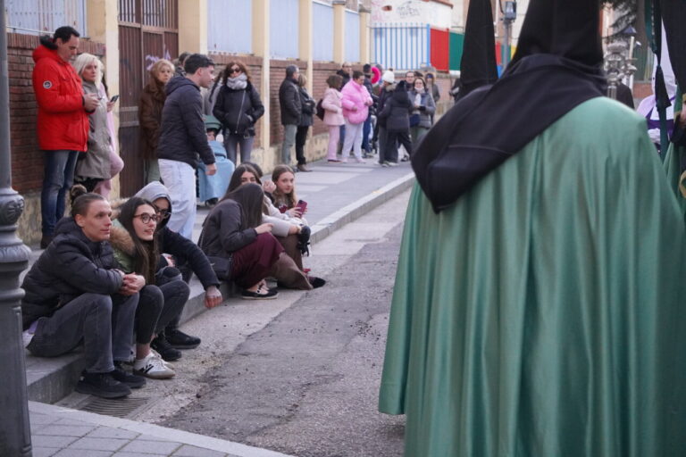 Personas sentadas en la acera durante la procesión del Sábado de Dolores en Palencia