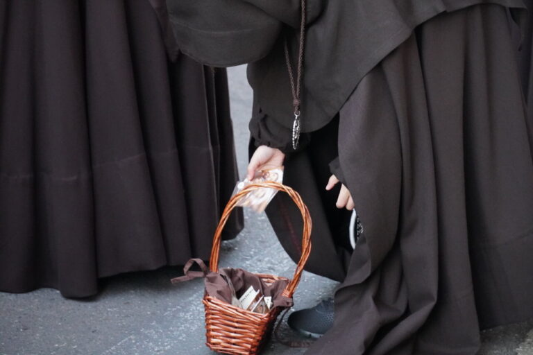 Persona con hábito religioso sosteniendo una cesta durante la procesión