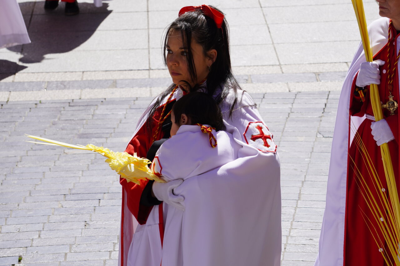Mujer con un niño en brazos durante la procesión de La Borriquilla en Palencia