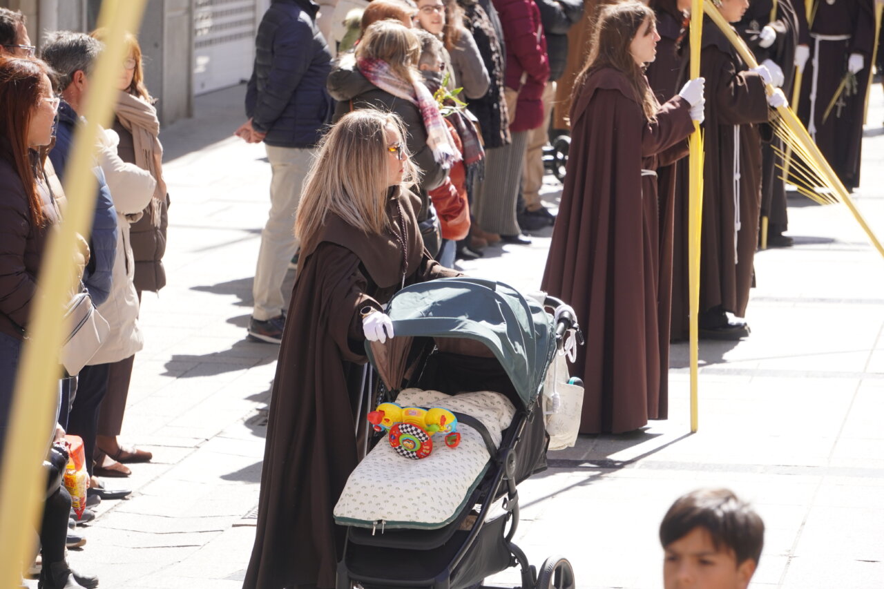Multitud en la procesión del Domingo de Ramos en Palencia con cofrades y niños.