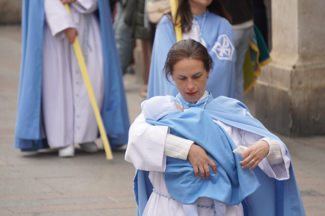 Mujer con un bebé en brazos durante la procesión del Domingo de Ramos en Palencia