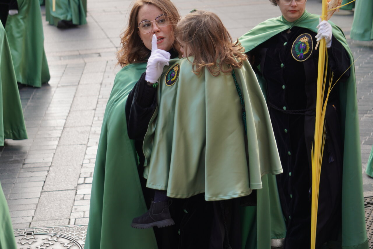 Mujer con capa verde y niña en procesión de Domingo de Ramos