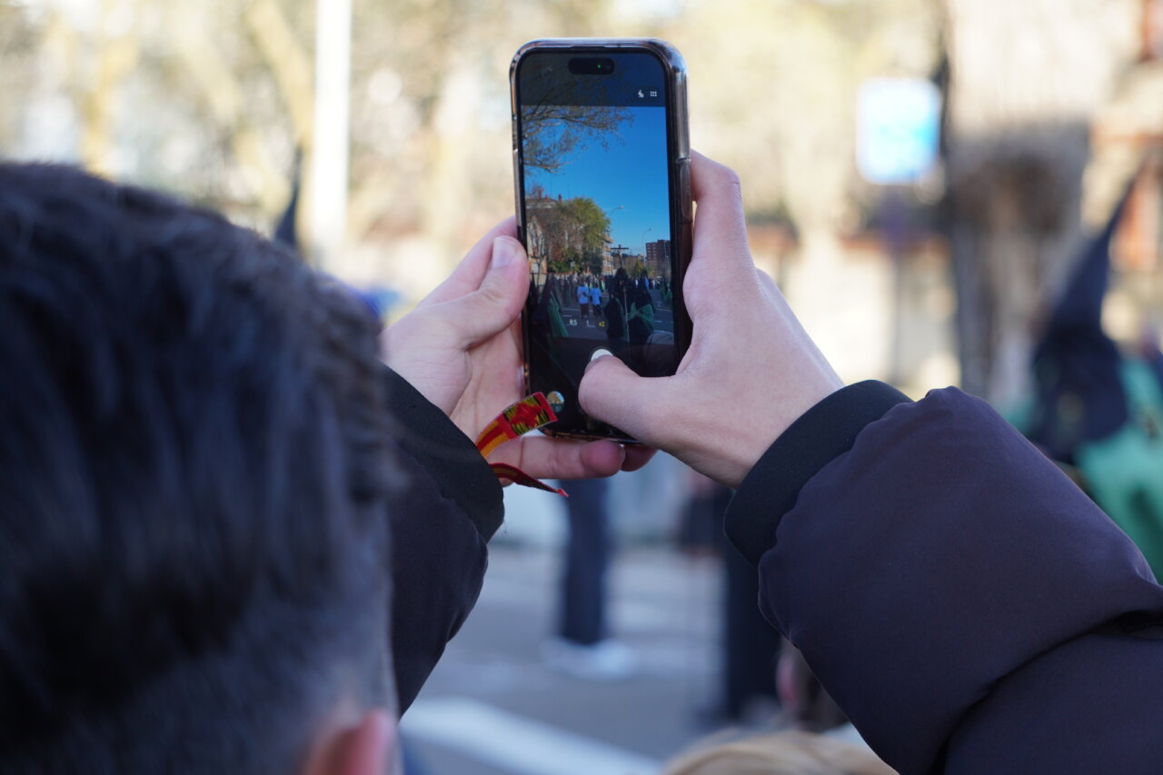 Persona tomando una foto durante la procesión del Rosario del Dolor en Palencia.