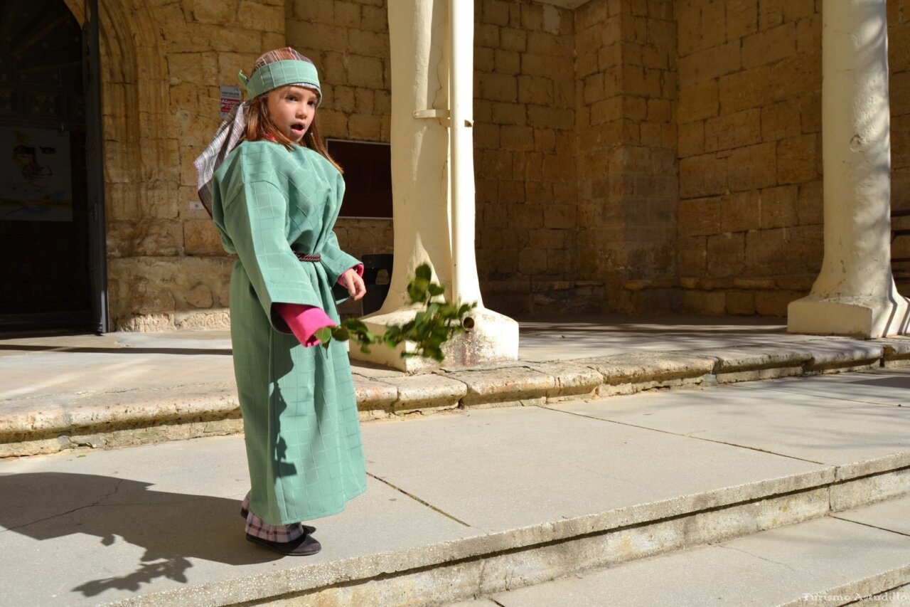 Niña vestida de procesión sosteniendo un ramo en Astudillo