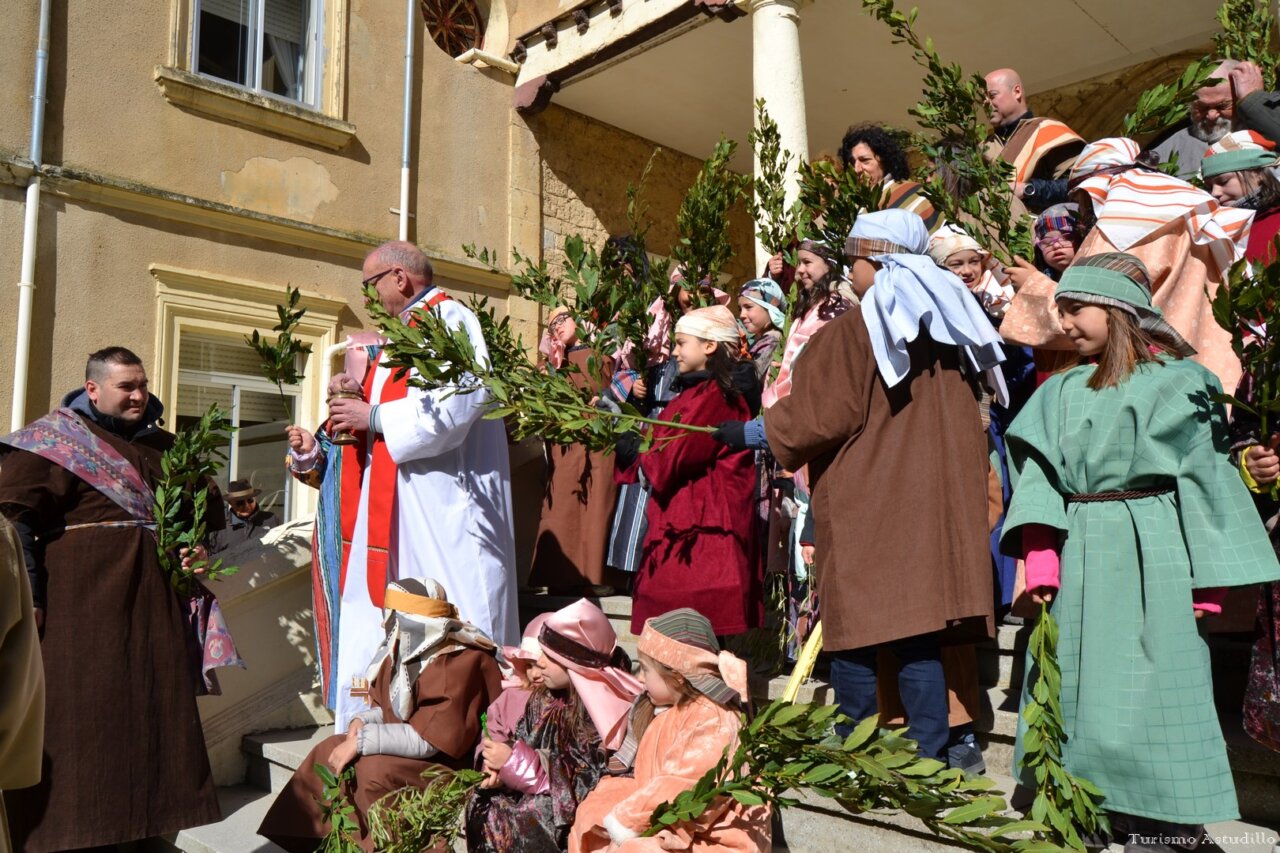 Celebración del Domingo de Ramos en Astudillo con personas y ramos.