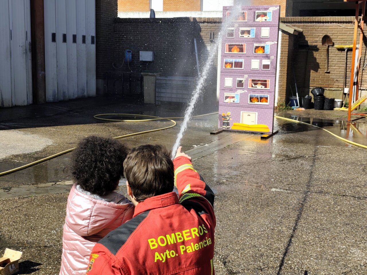 Niños intentando apagar un fuego simulado en el Parque de Bomberos de Palencia