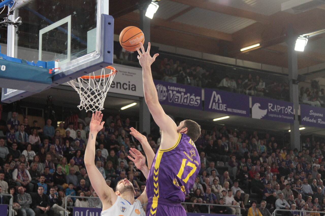 Jugador lanzando a canasta durante un partido de baloncesto