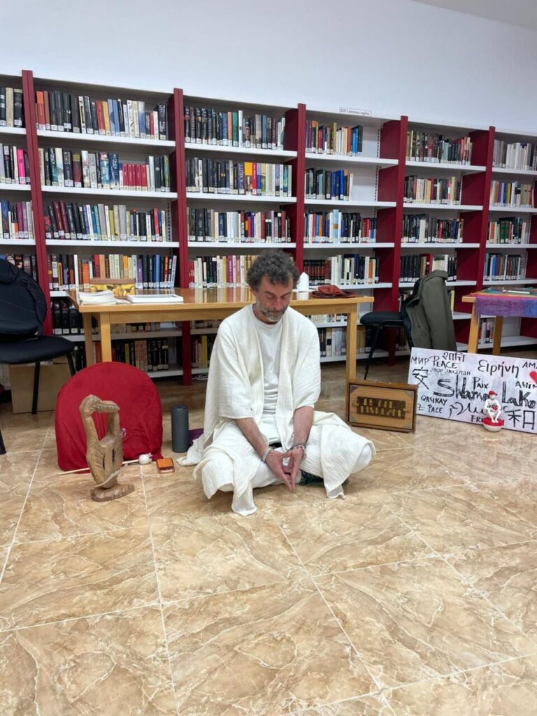 Hombre meditando en una biblioteca rodeado de libros