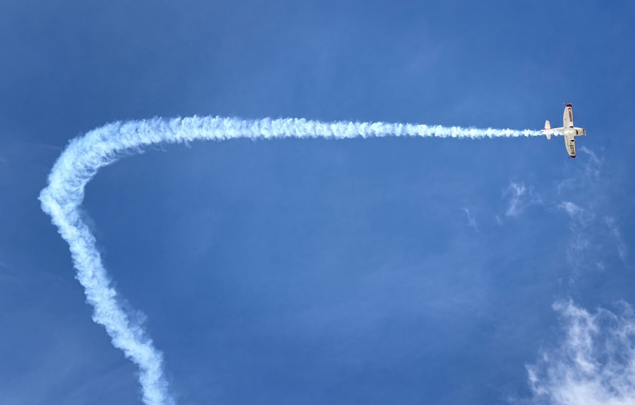 Avión realizando acrobacias aéreas en un cielo azul claro