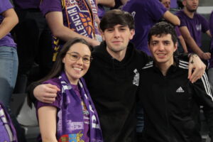 Aficionados del Palencia en un partido de baloncesto con bufandas moradas