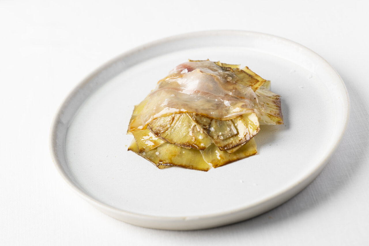 Plato de alcachofas confitadas con panceta ibérica y jugo de carne