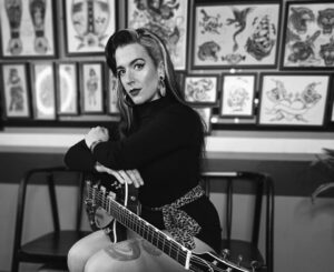 Anna Dukke posando con guitarra en un ambiente artístico