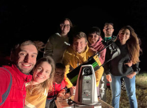 Grupo de personas con telescopio durante un evento astronómico nocturno