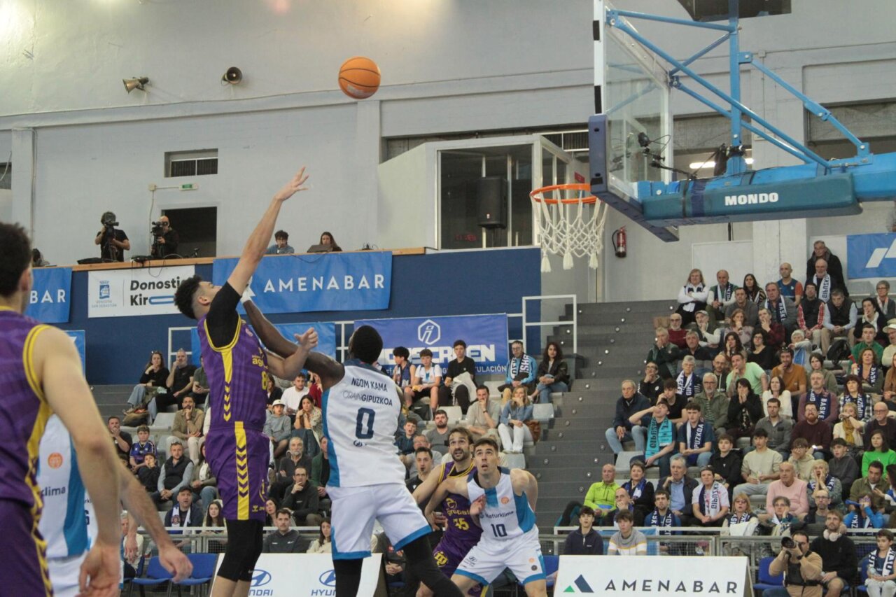 Jugador lanzando un balón de baloncesto en un partido emocionante