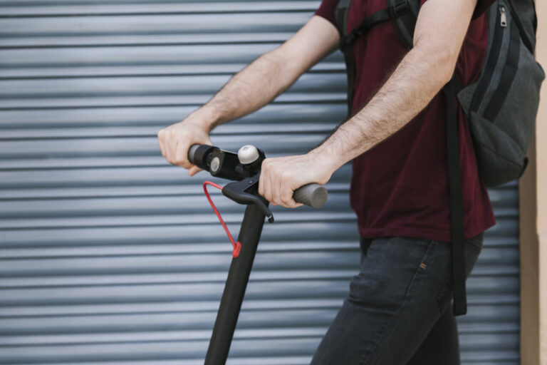 Conductor de patinete eléctrico en la calle con fondo gris