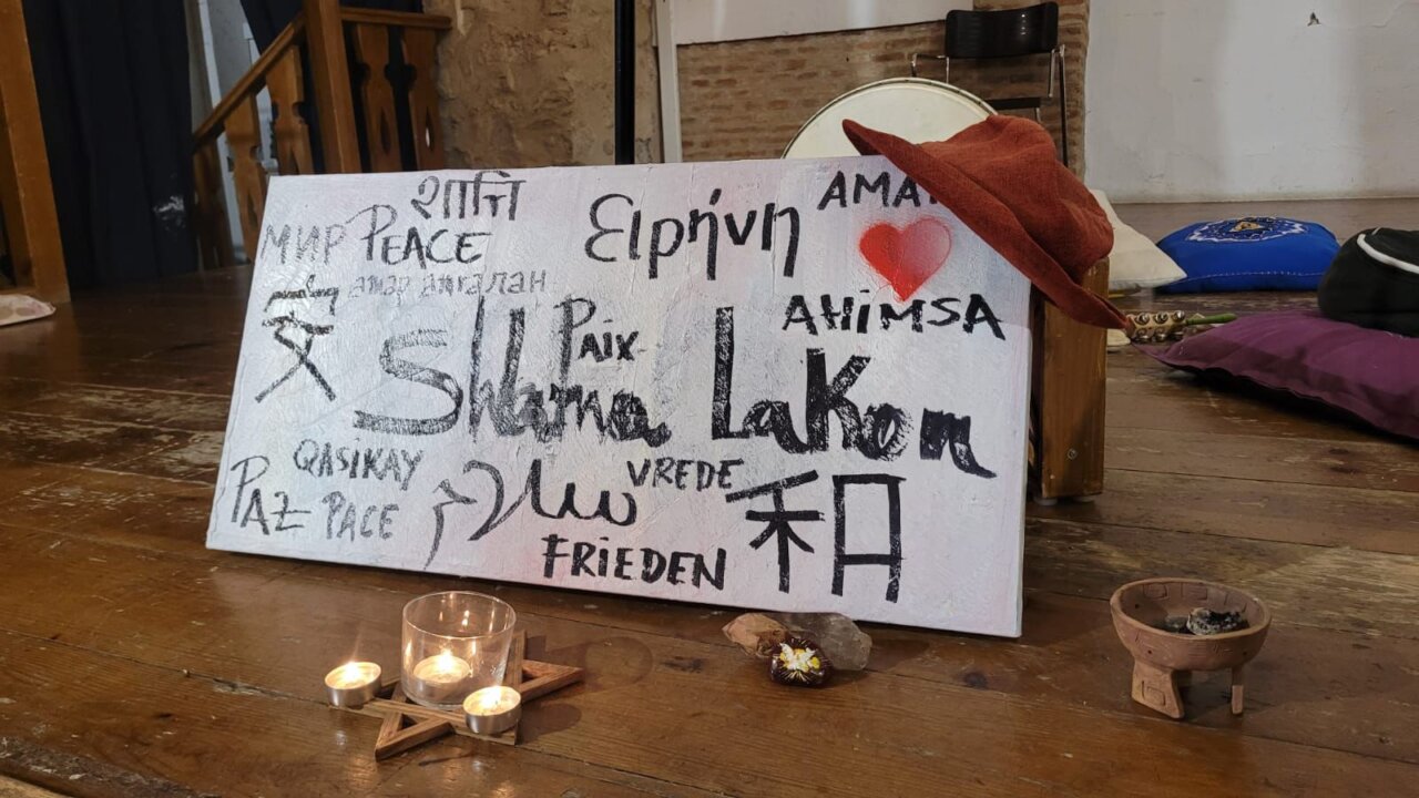 Cartel con palabras de paz en diferentes idiomas y velas encendidas