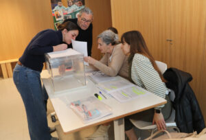 Personas revisando documentos en un centro de votación en Palencia