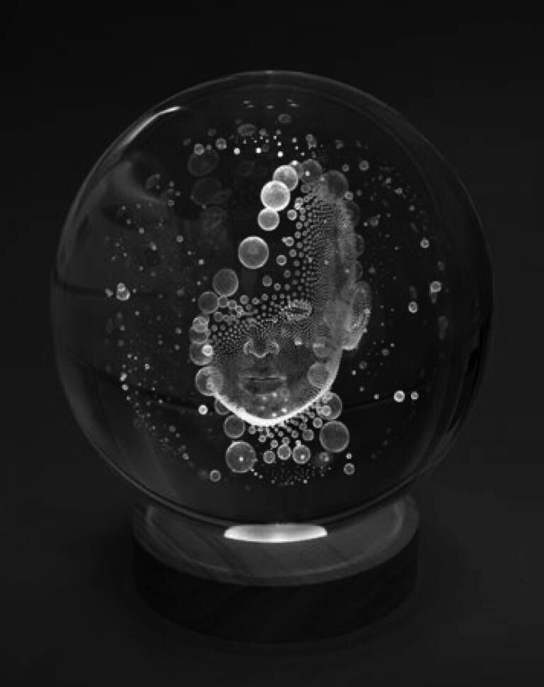 Esfera de cristal grabada con láser que muestra un rostro semihumano