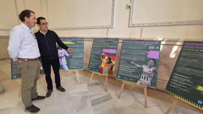 Dos hombres observando paneles de exposición sobre mujeres deportistas en Palencia