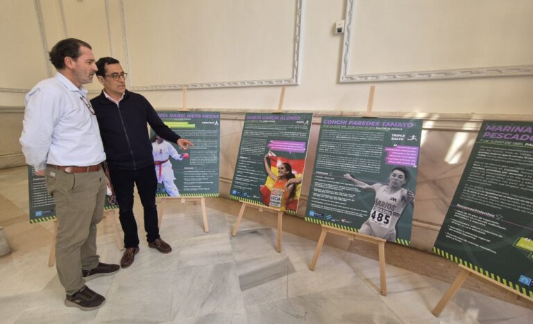 Dos hombres observando paneles de exposición sobre mujeres deportistas en Palencia