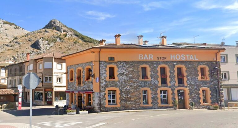 Exterior del Hostal Stop en la Montaña Palentina, con montañas al fondo.