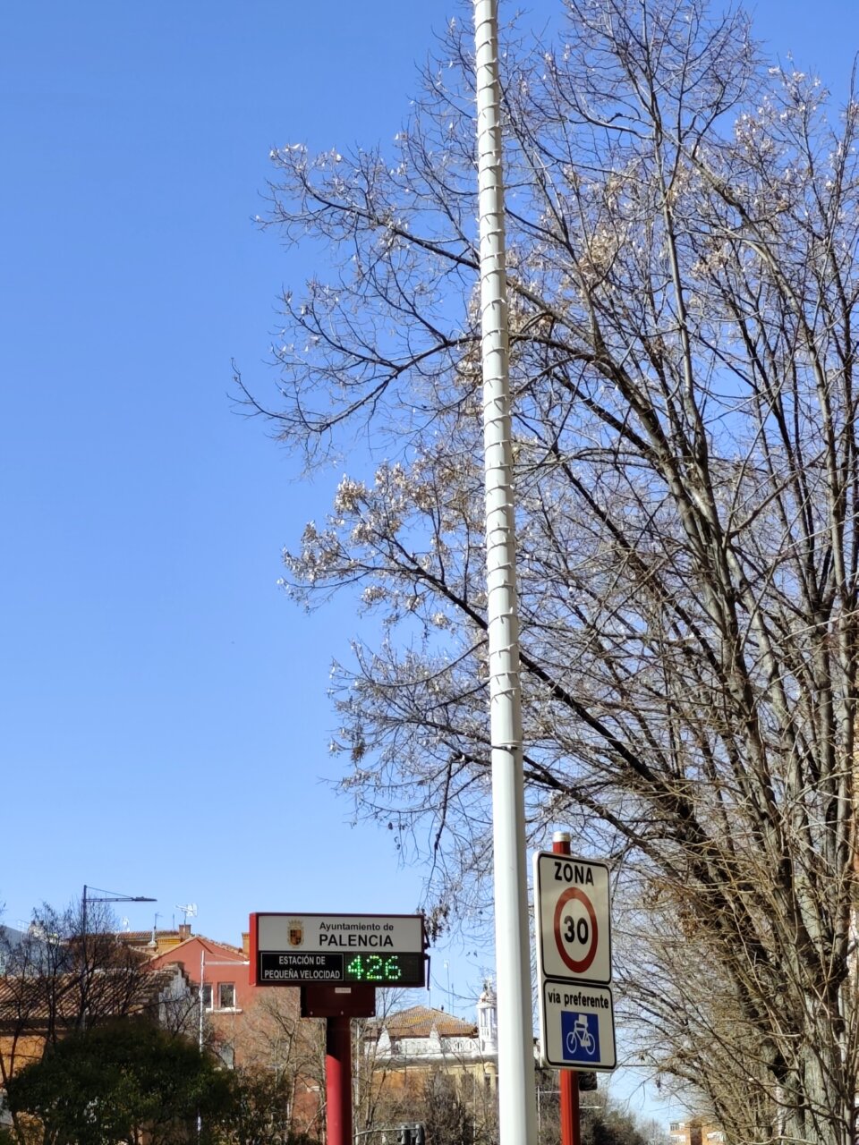 Farolas con luces navideñas en Palencia bajo un cielo azul