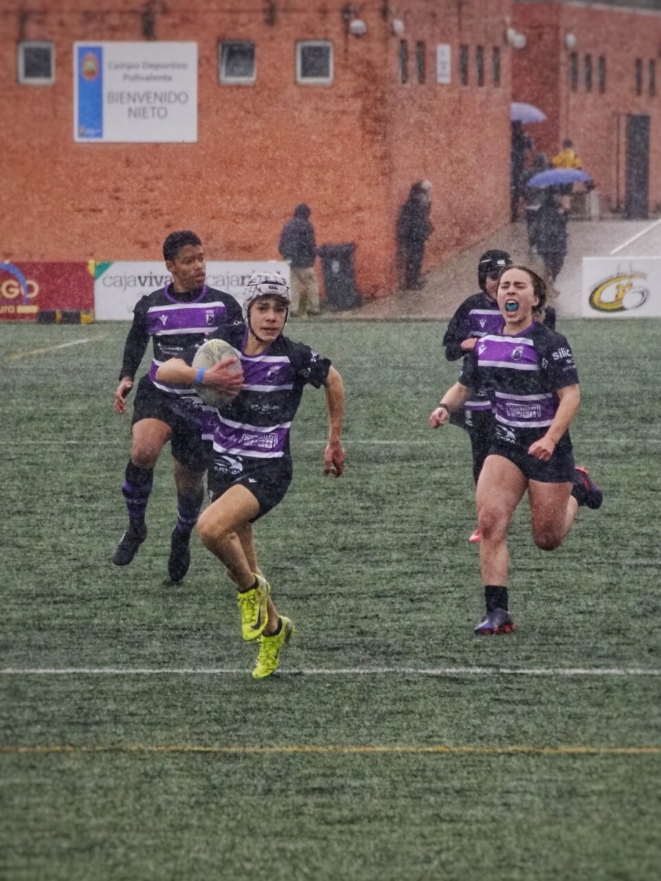 Jugadores de rugby del sub-12 y sub-14 en un partido bajo la lluvia