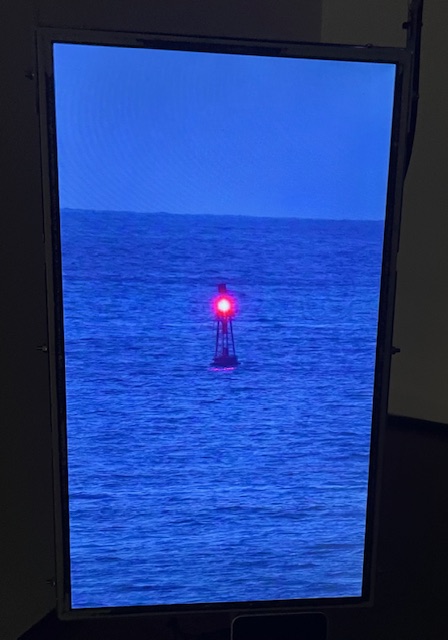 Instalación artística con faro rojo en el mar