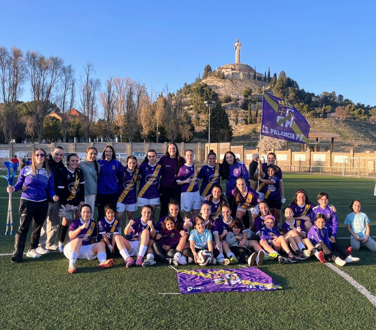 Jugadoras del Palencia Fútbol Femenino celebrando una victoria con una bandera del equipo.