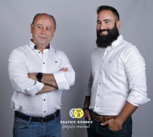 Retrato de dos hombres en camisa blanca, sonriendo y posando.