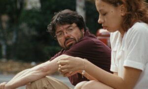 Escena de la película Un poeta con un hombre y una mujer sentados