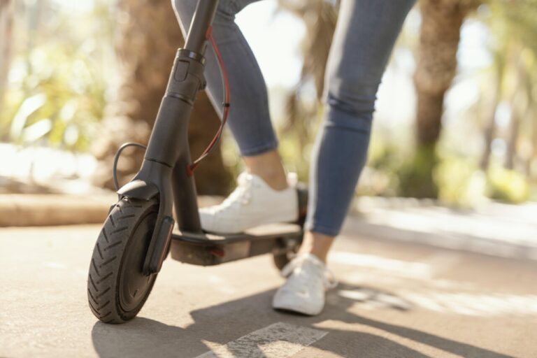 Mujer joven montando un patinete eléctrico en la ciudad