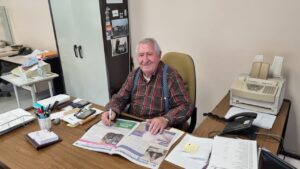 Paco Álvarez de la Lama sentado en su oficina leyendo un periódico