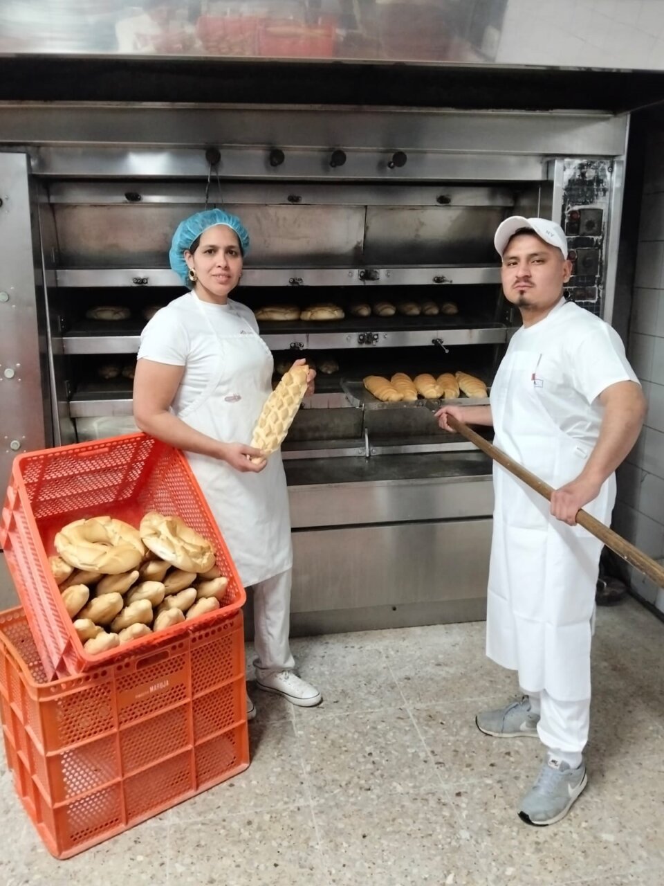 Empleados de la Panadería Maruja sosteniendo pan fresco en el horno