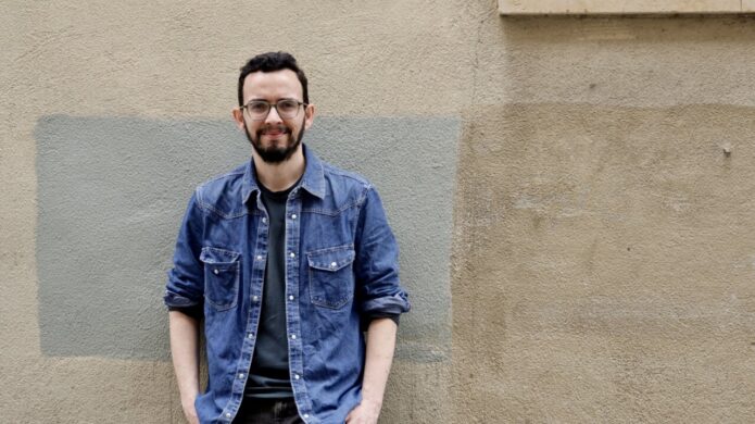 Miguel Ángel Llamas posando frente a una pared con colores neutros