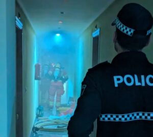 Policía local observando a bomberos en un pasillo con humo