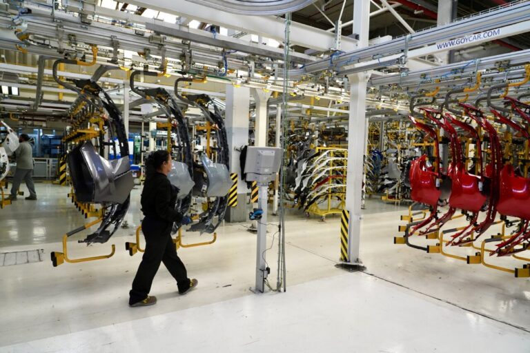 Trabajadores en una línea de producción de Renault con piezas de automóviles