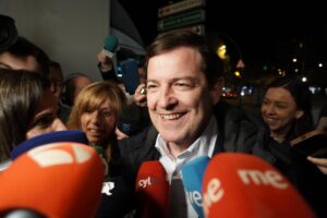 Persona sonriendo rodeada de micrófonos en un evento electoral