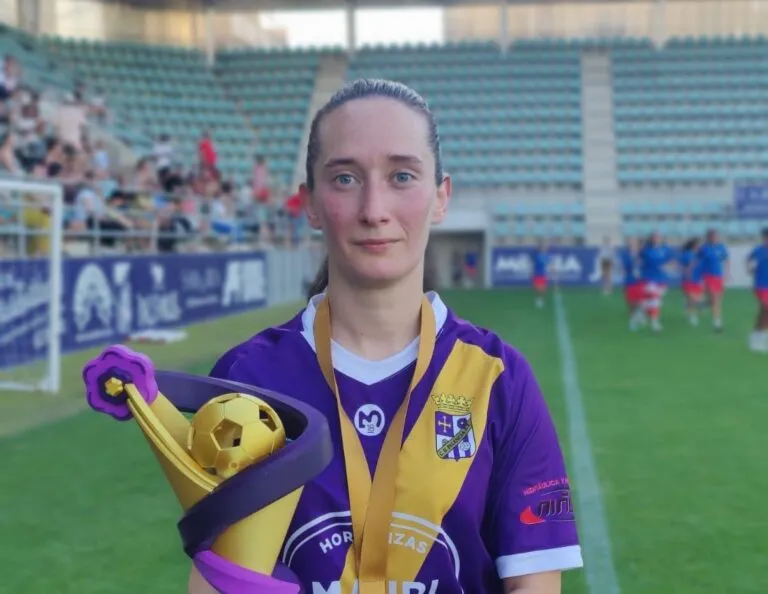 Sara León sosteniendo un trofeo en un campo de fútbol
