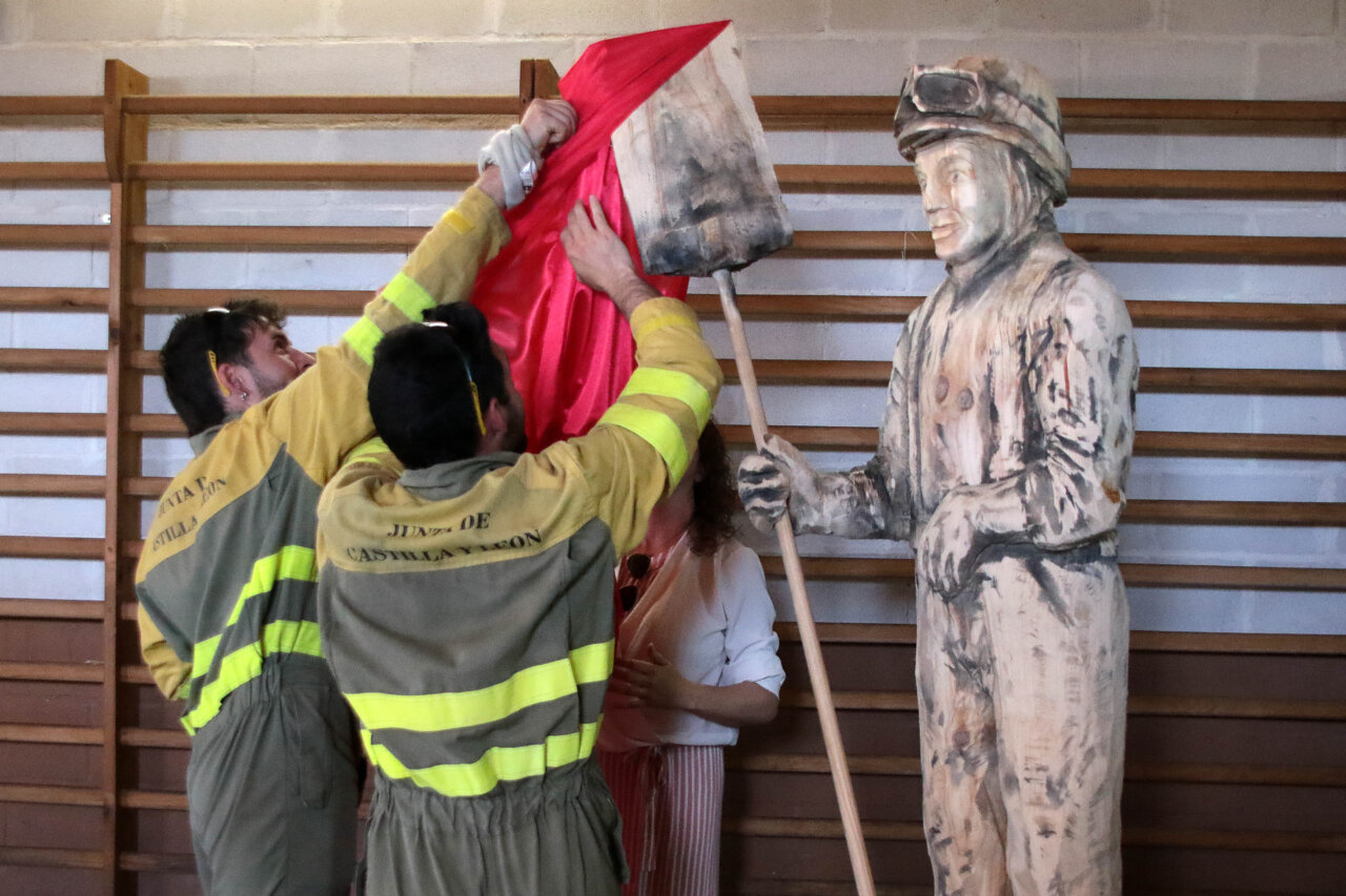Dos hombres descubriendo una escultura en homenaje a brigadas forestales
