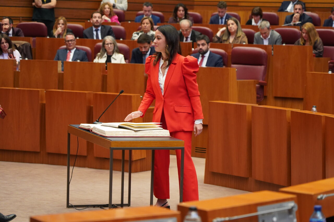 Una mujer en traje rojo habla en el hemiciclo de las Cortes de Castilla y León.