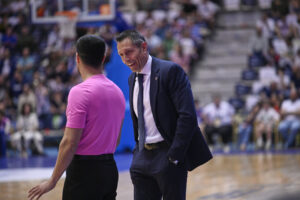 Entrenador del Monbus Obradoiro conversando con un árbitro durante un partido de baloncesto.